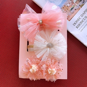 Detailed view of pink mesh bow and floral headbands set on a display card for babies