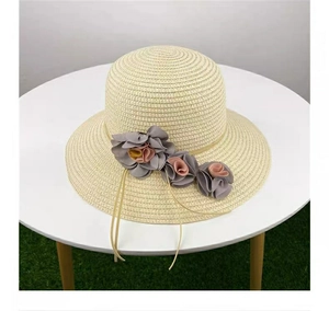 Close-up of beige straw sun hat featuring pink and grey fabric floral decorations