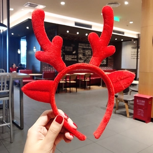 Close-up of a festive red plush Christmas reindeer antler headband with soft fabric ears