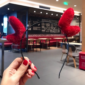 Close-up of a festive headband featuring plush red hearts on a thin black frame