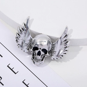 Detail of vintage silver winged skull brooch with textured metallic finish and gothic style