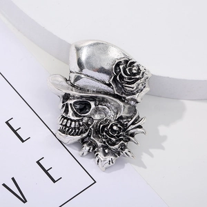 Detail shot of a vintage silver skull brooch with a top hat and intricate roses decoration
