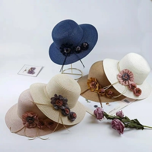 Close-up of assorted foldable woven sun hats with decorative flowers in five colors
