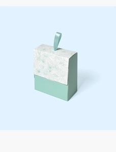 Close-up of a mini light green floral gift box with a delicate ribbon pull tab