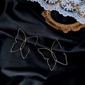 Dettaglio di orecchini a farfalla geometrici placcati oro 14K su raso nero