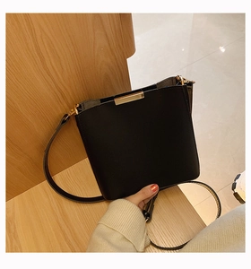 Close-up of minimalist black leather bucket bag featuring elegant gold metal hardware