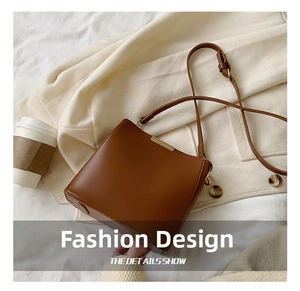 Close-up of brown leather bucket bag with gold metal buckle on a beige sweater