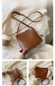 Close-up of a brown leather bucket bag with gold metal trim and adjustable strap details