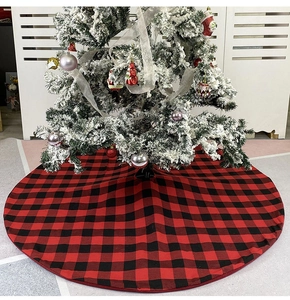 Detailed view of classic red and black plaid Christmas tree skirt under a festive tree