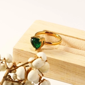 Minimalist 18k gold heart ring with green zircon on a wooden display stand