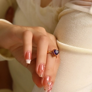 Detail shot of heart-shaped purple zircon ring in gold plating on model's finger