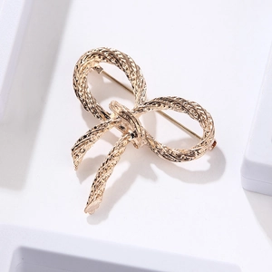 Detailed view of golden bowknot brooch featuring intricate rope texture and metallic finish