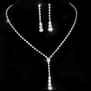 Detailed view of silver necklace and drop earrings set with shimmering crystals