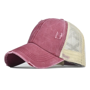 Détail de la casquette rouge délavée avec trous usés et filet beige respirant à l'arrière