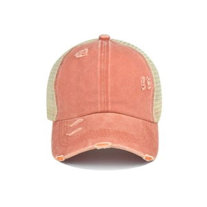 Détail macro du tissu orange vieilli et du mesh beige respirant sur la casquette baseball