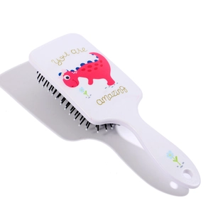 Detail of white plastic cushion hairbrush featuring cute cartoon dinosaur and floral patterns