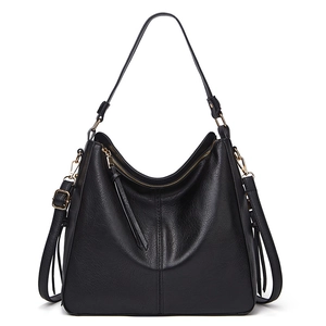 Fashionable black faux leather tote bag with gold hardware and side tassels on white background