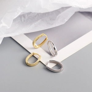 Macro detail of minimalist S925 sterling silver U-shaped hoop earrings in gold and silver