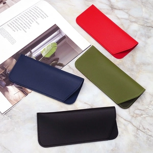 Flat lay of multiple faux leather sunglass pouches in various colors on a marble surface
