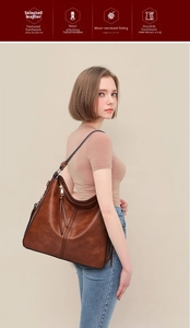 Detail view of large caramel brown leather hobo bag with long fringe tassel zipper charm