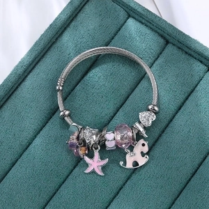 Silver charm bracelet with pink enamel starfish and purple crystal on a green display