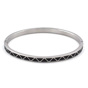 Macro detail of silver stainless steel bangle with black enamel triangle geometric pattern