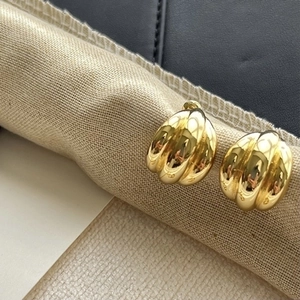 Polished gold multi-layer C-shaped croissant earrings on a textured linen display