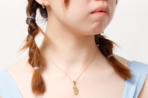 Dettaglio modella con collana pendente a ippocampo dorato e set di orecchini abbinati