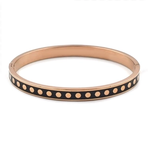 Detail view of rose gold stainless steel bangle with black enamel and gold dot patterns