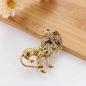 Vintage gold lion brooch with detailed mane on natural wood background with white flowers
