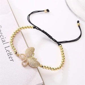 Detailed view of zircon butterfly charm with gold beads and black braided adjustable cord