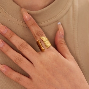 Close-up of golden wide open ring with unique hammered texture and metallic finish