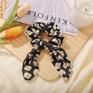 Detail shot of leopard print scrunchie with long ribbon on a wooden tray with tulips