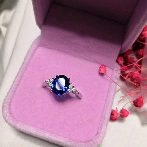 Oval royal blue gemstone ring with side stones in a purple velvet jewelry box
