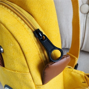 Close-up of yellow canvas fabric texture with gold zipper and leather puller detail