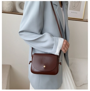 Detailed close-up of a vintage brown leather crossbody bag with a gold button closure