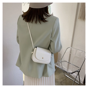 Back view of model wearing white leather half-moon crossbody bag with gold buckle
