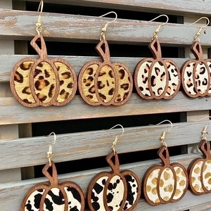 Pendientes de cuero con forma de calabaza y estampados de leopardo sobre fondo de madera natural