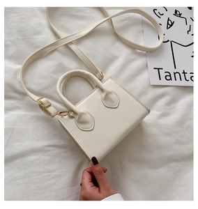 Detailansicht einer weißen Mini-Trapeztasche mit rundem Griff und Goldbeschlägen