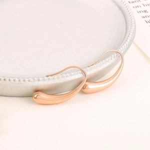Elegant rose gold water drop earrings in irregular geometric design on a white ceramic plate