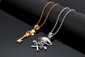 Detail of skull necklaces with key and pistols pendants in gold and silver finish