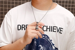 Detailed view of men's silver boxing glove pendant with twisted chain on a model