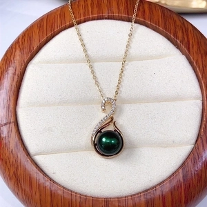 Elegant gold necklace featuring a dark green pearl pendant with cubic zirconia accents
