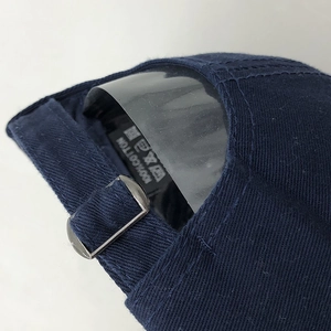 Close-up of navy blue cotton baseball cap showing metal buckle and 100% cotton tag
