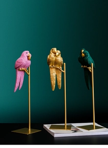 Detail of artistic resin parrot statues with textured feathers on gold metal stands