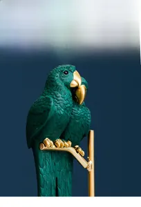 Close-up of dark green resin parrot figurines with detailed feather texture and gold accents