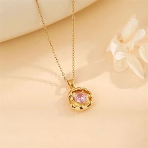 Detailed close-up of pink heart-shaped gemstone pendant with hammered gold texture border