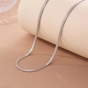 Sleek silver stainless steel snake bone chain necklace displayed on a beige stand