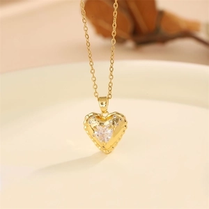 Golden stainless steel heart pendant necklace with sparkling cubic zirconia on a white plate