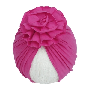 Bonnet turban rose en tricot pour bébé avec une grande fleur plissée sur fond blanc